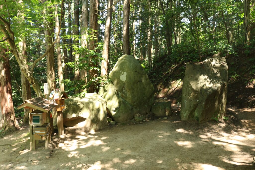 The entrance to Yomotsuhirasaka (the slope to the underworld) in Iya, Higashiizumo, Matsue City, Shimane Prefecture, featuring sacred rocks and a small wooden shrine surrounded by forest.