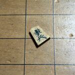 A single shogi piece labeled “歩兵” (foot soldier) lying slightly tilted on a wooden shogi board — symbolizing that even the smallest piece holds unique value.